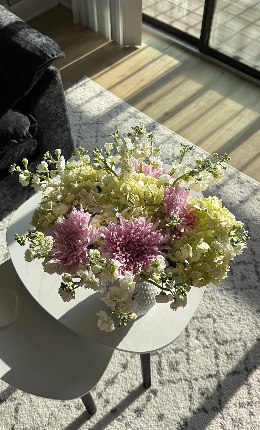 An abundant arrangement of lilac flowers and fresh green hydrangeas in sunlight